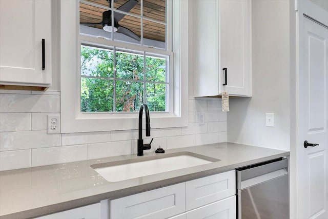 kitchen featuring stainless steel dishwasher, sink, backsplash, and white cabinetry