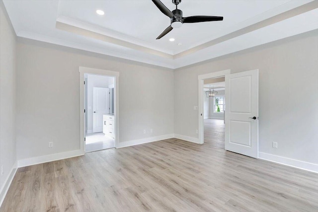 empty room featuring a tray ceiling, ornamental molding, ceiling fan, and light hardwood / wood-style floors