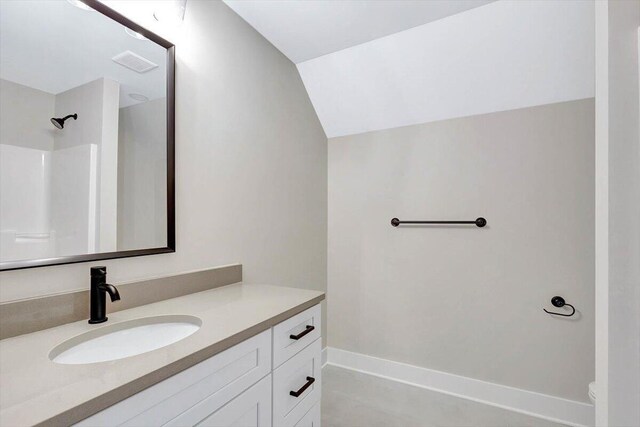 bathroom with vanity, vaulted ceiling, a shower, and toilet