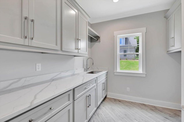 laundry room featuring crown molding, light hardwood / wood-style flooring, and sink