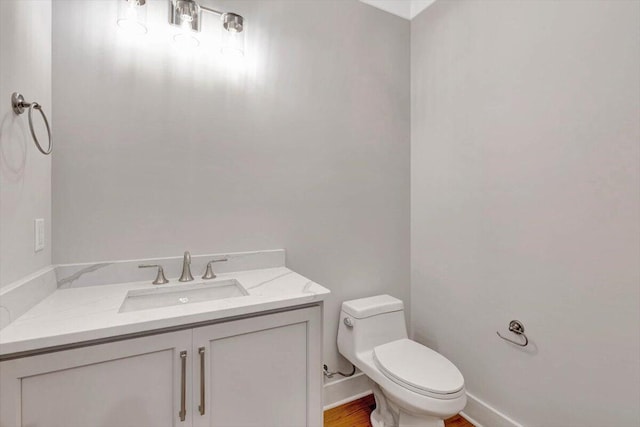 bathroom featuring wood-type flooring, toilet, and vanity