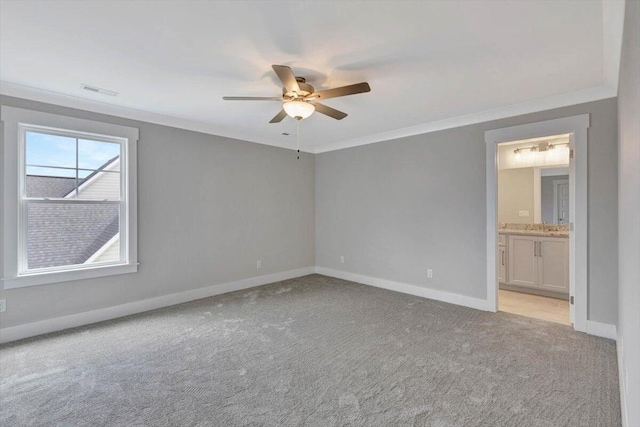 unfurnished bedroom featuring crown molding, ceiling fan, ensuite bath, and light carpet