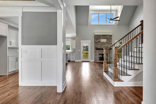 entryway featuring a fireplace, dark wood-type flooring, a wealth of natural light, and a high ceiling