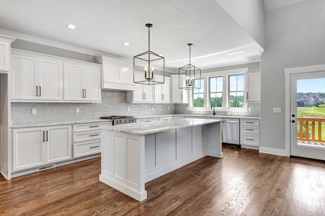 kitchen with appliances with stainless steel finishes, a center island, white cabinets, and custom exhaust hood