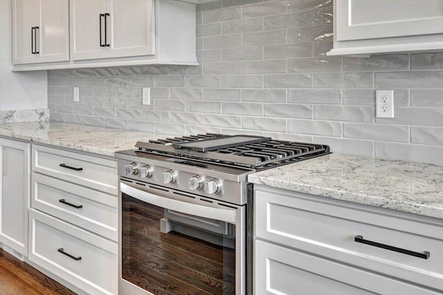 kitchen featuring high end stainless steel range oven, hardwood / wood-style flooring, light stone countertops, and tasteful backsplash