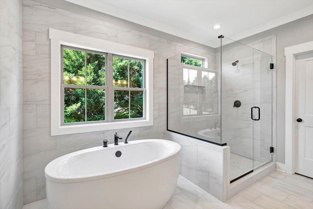 bathroom featuring tile walls, independent shower and bath, and plenty of natural light