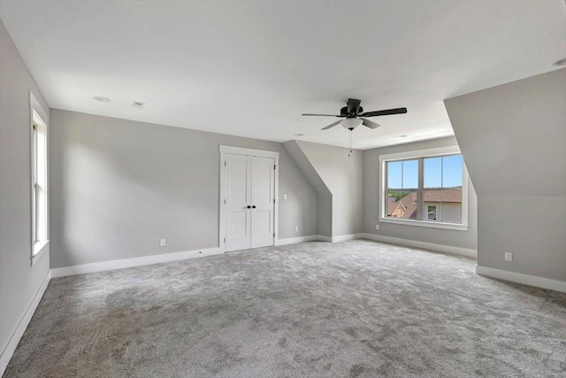 bonus room with ceiling fan and carpet