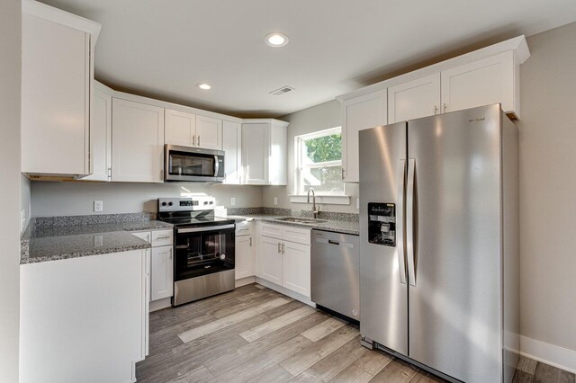 kitchen featuring white cabinets, appliances with stainless steel finishes, light wood-type flooring, and sink