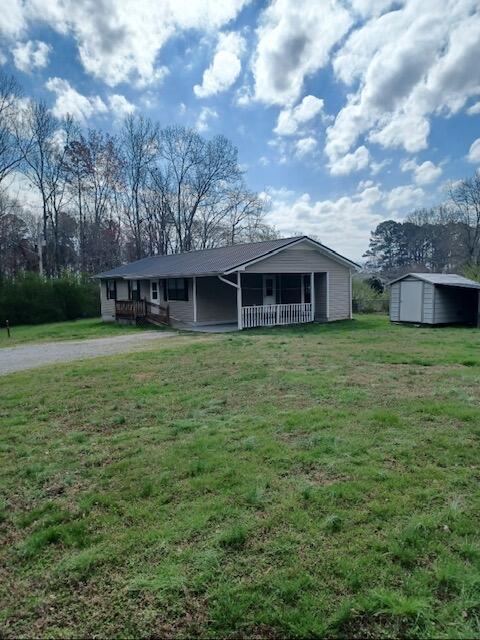 ranch-style house featuring a front yard, a porch, and a shed