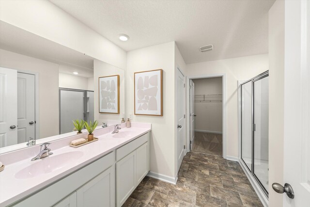 bathroom with an enclosed shower, a textured ceiling, and vanity