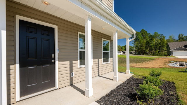 entrance to property featuring a lawn and covered porch