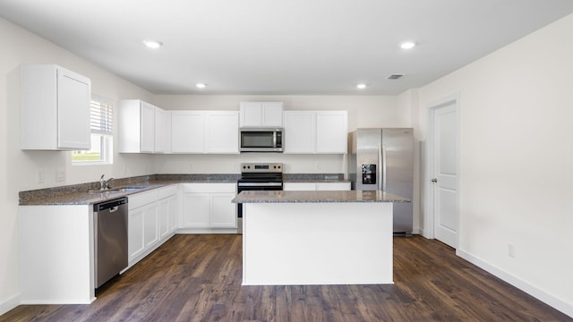 kitchen featuring appliances with stainless steel finishes, dark hardwood / wood-style flooring, white cabinetry, and a center island