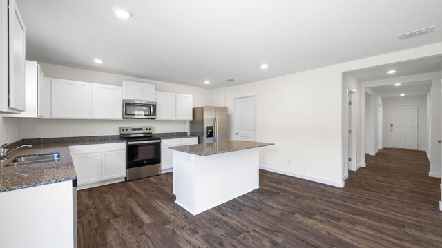 kitchen featuring white cabinetry, stainless steel appliances, a center island, dark hardwood / wood-style floors, and sink