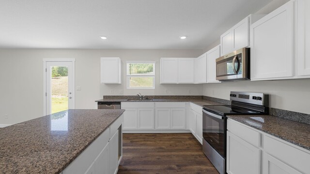 kitchen featuring appliances with stainless steel finishes, white cabinetry, dark wood-type flooring, and plenty of natural light