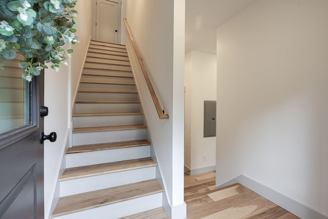 staircase with hardwood / wood-style flooring and electric panel