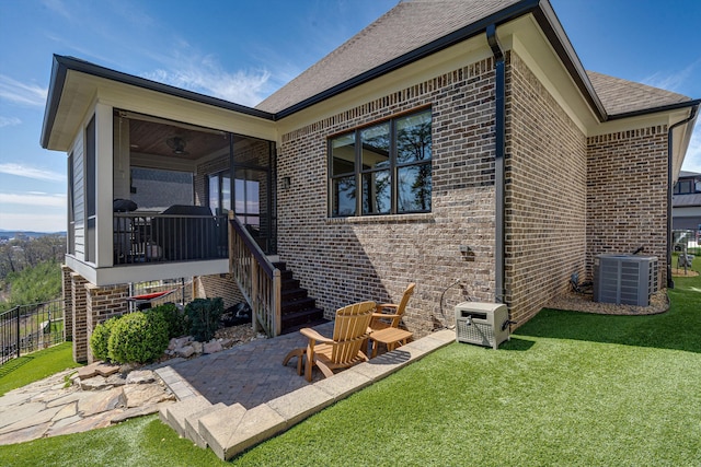 rear view of house featuring central AC, a sunroom, a yard, and a patio area