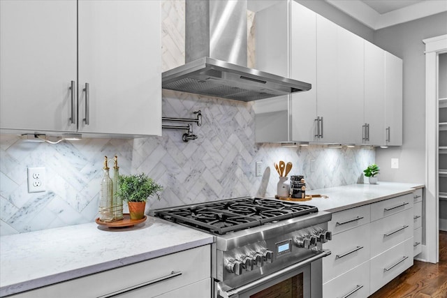 kitchen featuring decorative backsplash, wall chimney exhaust hood, stainless steel stove, white cabinetry, and dark hardwood / wood-style floors