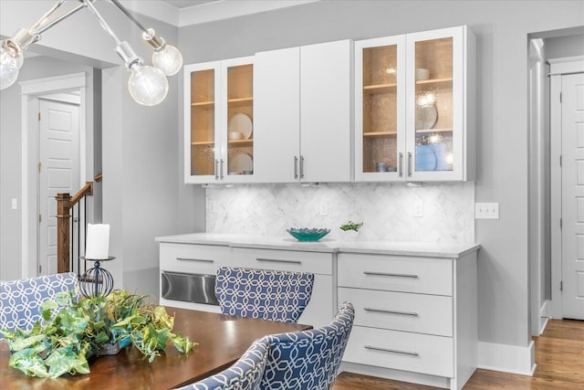 interior space with decorative backsplash, light stone counters, white cabinetry, and dark wood-type flooring