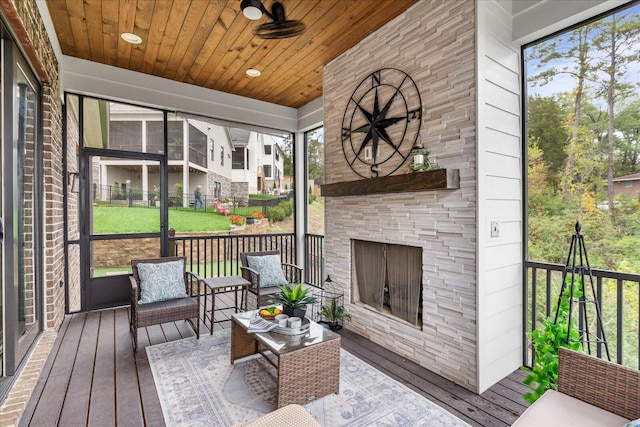 sunroom featuring an outdoor stone fireplace and wood ceiling