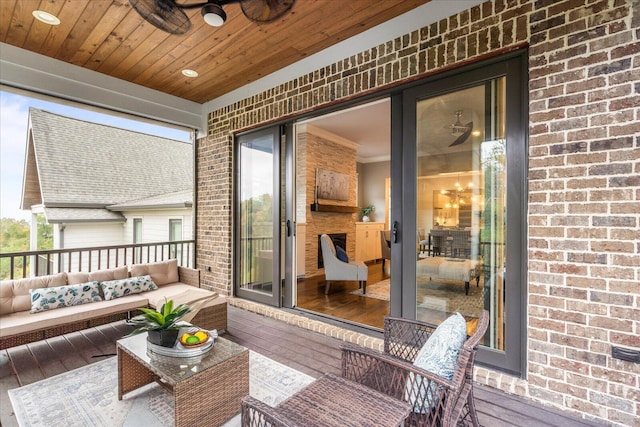 wooden terrace featuring an outdoor living space, ceiling fan, and covered porch