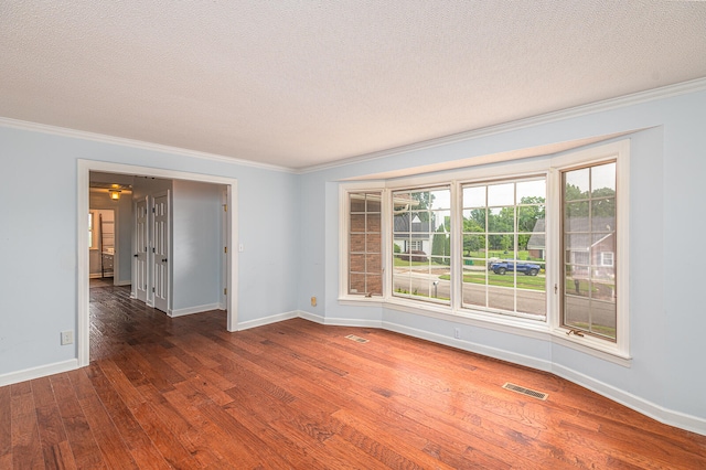 empty room featuring ornamental molding, dark hardwood / wood-style flooring, and a textured ceiling