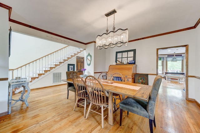 dining room with light hardwood / wood-style flooring, ornamental molding, and a notable chandelier