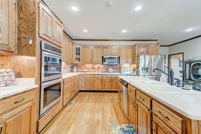 kitchen featuring sink, stainless steel appliances, backsplash, crown molding, and light hardwood / wood-style floors