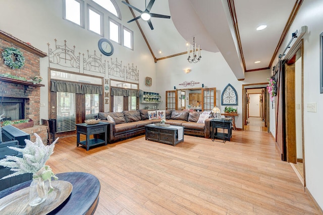 living room featuring ceiling fan with notable chandelier, crown molding, a barn door, a towering ceiling, and light hardwood / wood-style floors