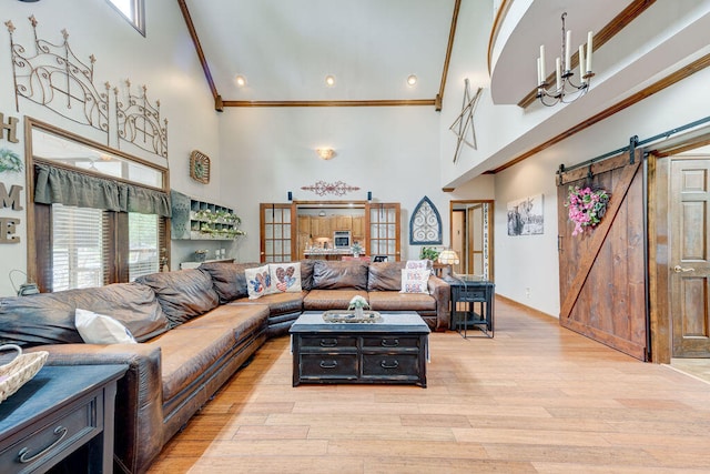 living room with a high ceiling, a barn door, light hardwood / wood-style floors, and a healthy amount of sunlight