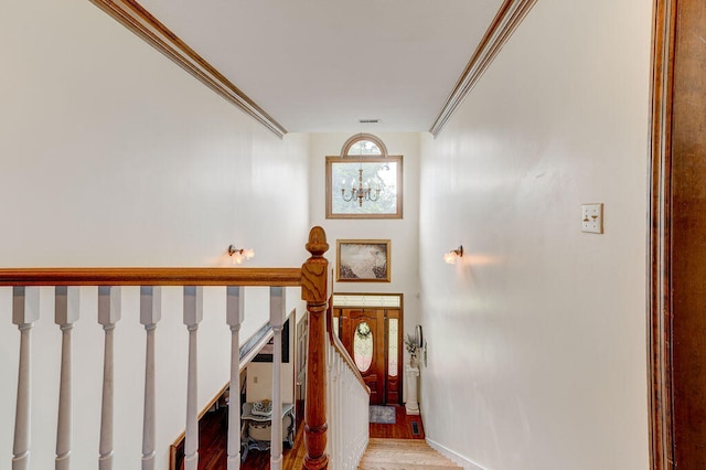 staircase with crown molding, hardwood / wood-style floors, and a chandelier