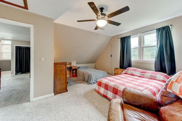 carpeted bedroom with ceiling fan, vaulted ceiling, and multiple windows