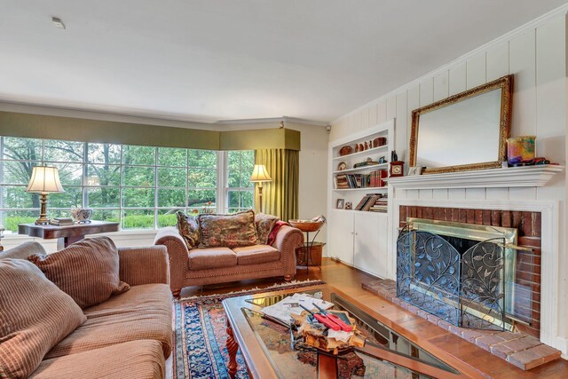 living room with ornamental molding, a brick fireplace, hardwood / wood-style floors, and built in shelves