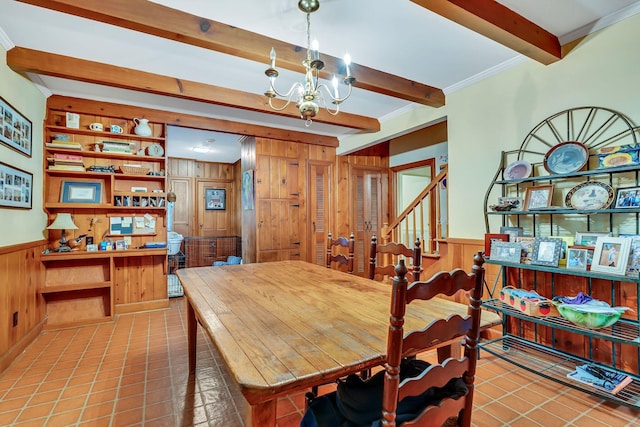 dining space featuring a notable chandelier, light tile patterned flooring, wood walls, beam ceiling, and ornamental molding