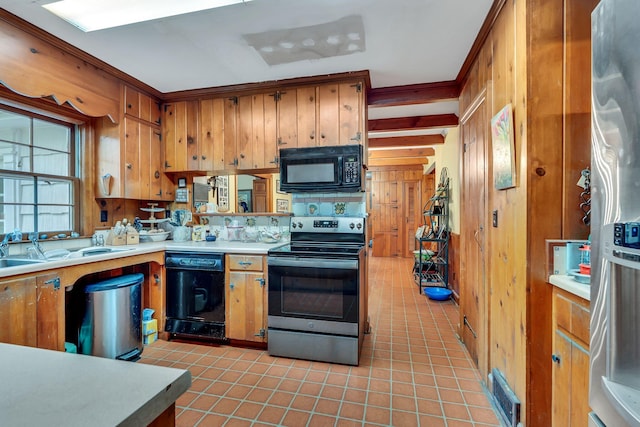 kitchen featuring wooden walls, ornamental molding, light tile patterned floors, black appliances, and sink