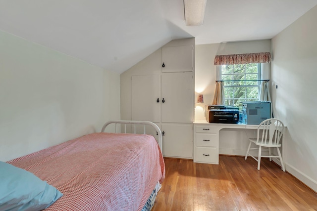 bedroom with lofted ceiling, light hardwood / wood-style flooring, and built in desk