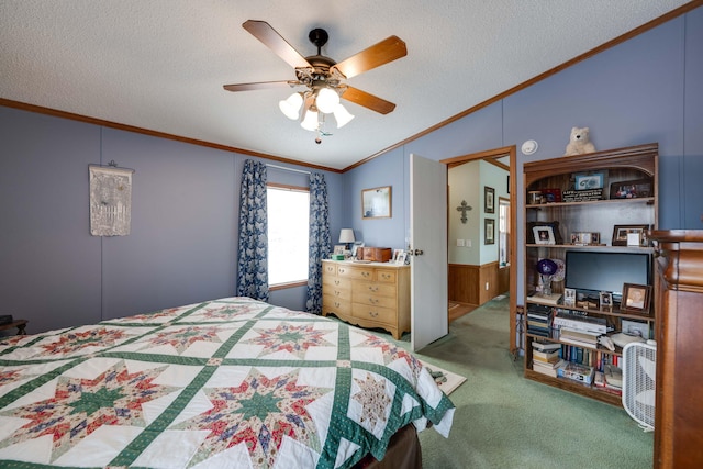 bedroom with wood walls, carpet floors, ceiling fan, ornamental molding, and a textured ceiling