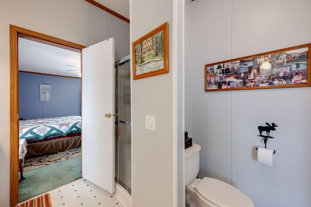 bathroom with toilet, an enclosed shower, and ornamental molding