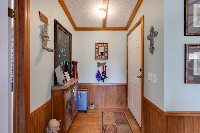 doorway to outside with a textured ceiling, ornamental molding, and hardwood / wood-style floors