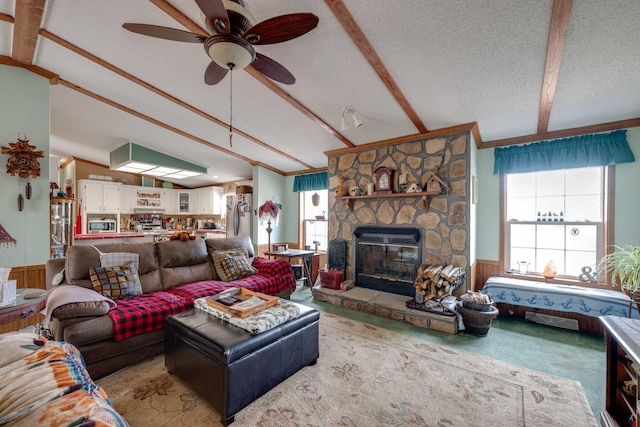 living room with wood walls, ceiling fan, a wealth of natural light, a fireplace, and a textured ceiling