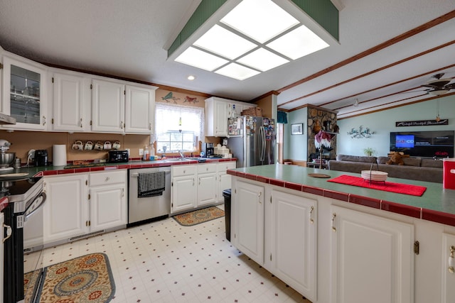 kitchen featuring stainless steel refrigerator, white cabinets, dishwasher, and tile counters