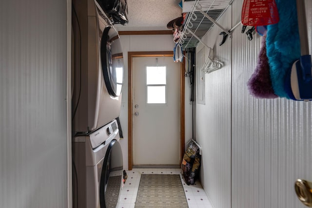 laundry room featuring stacked washer and clothes dryer, a textured ceiling, and crown molding