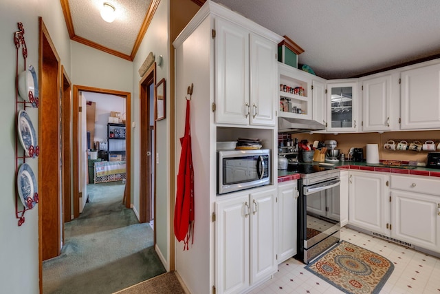 kitchen featuring a textured ceiling, stainless steel appliances, white cabinetry, and ornamental molding