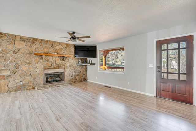 unfurnished living room featuring a fireplace, a textured ceiling, hardwood / wood-style flooring, and ceiling fan