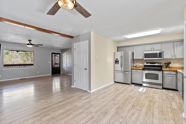 kitchen featuring ceiling fan, gray cabinetry, appliances with stainless steel finishes, and beam ceiling