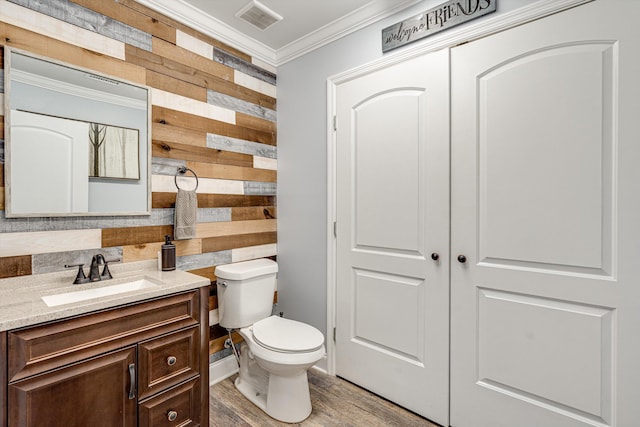 bathroom with wooden walls, hardwood / wood-style floors, toilet, vanity, and ornamental molding