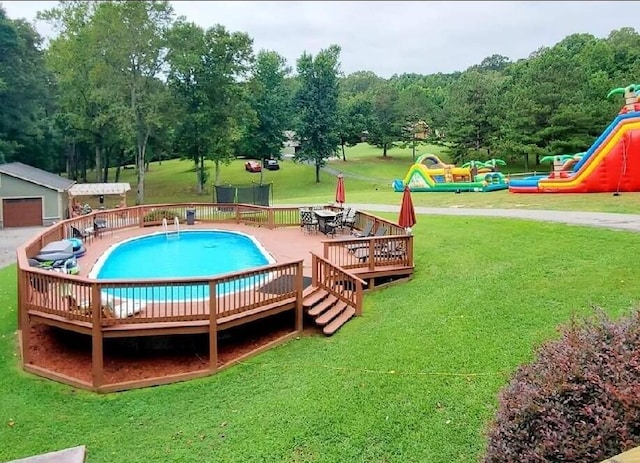 view of swimming pool with a wooden deck, an outdoor structure, and a yard