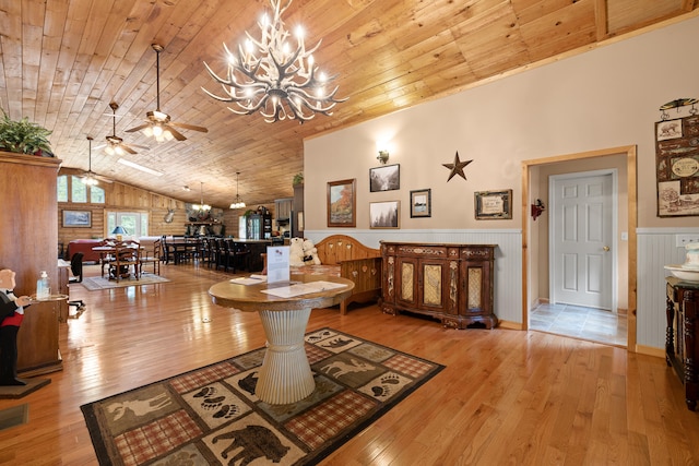 living room featuring light wood-type flooring, wooden walls, ceiling fan with notable chandelier, wood ceiling, and lofted ceiling