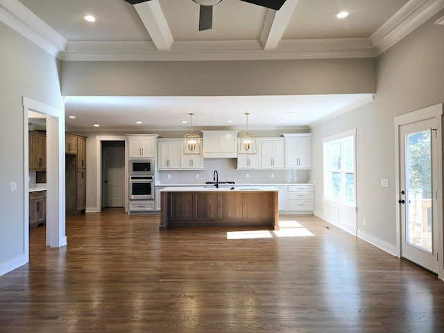 kitchen with white cabinets, dark hardwood / wood-style flooring, stainless steel appliances, and a large island with sink