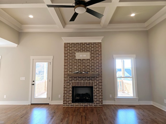 unfurnished living room featuring ceiling fan, dark wood-type flooring, coffered ceiling, a brick fireplace, and ornamental molding