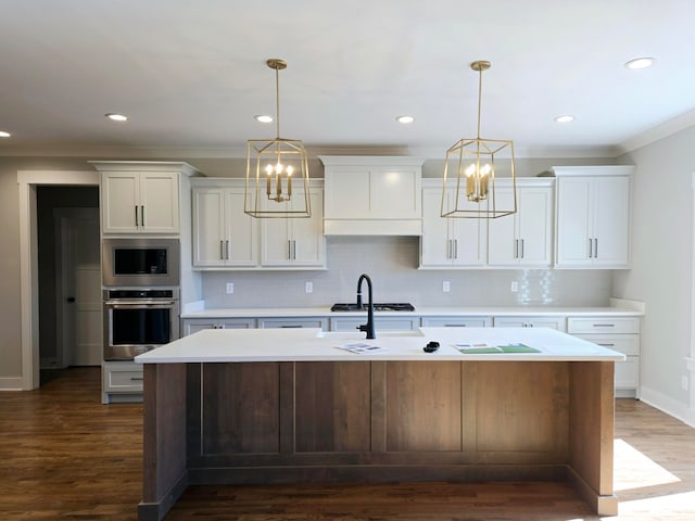 kitchen with decorative backsplash, appliances with stainless steel finishes, a kitchen island with sink, and dark wood-type flooring